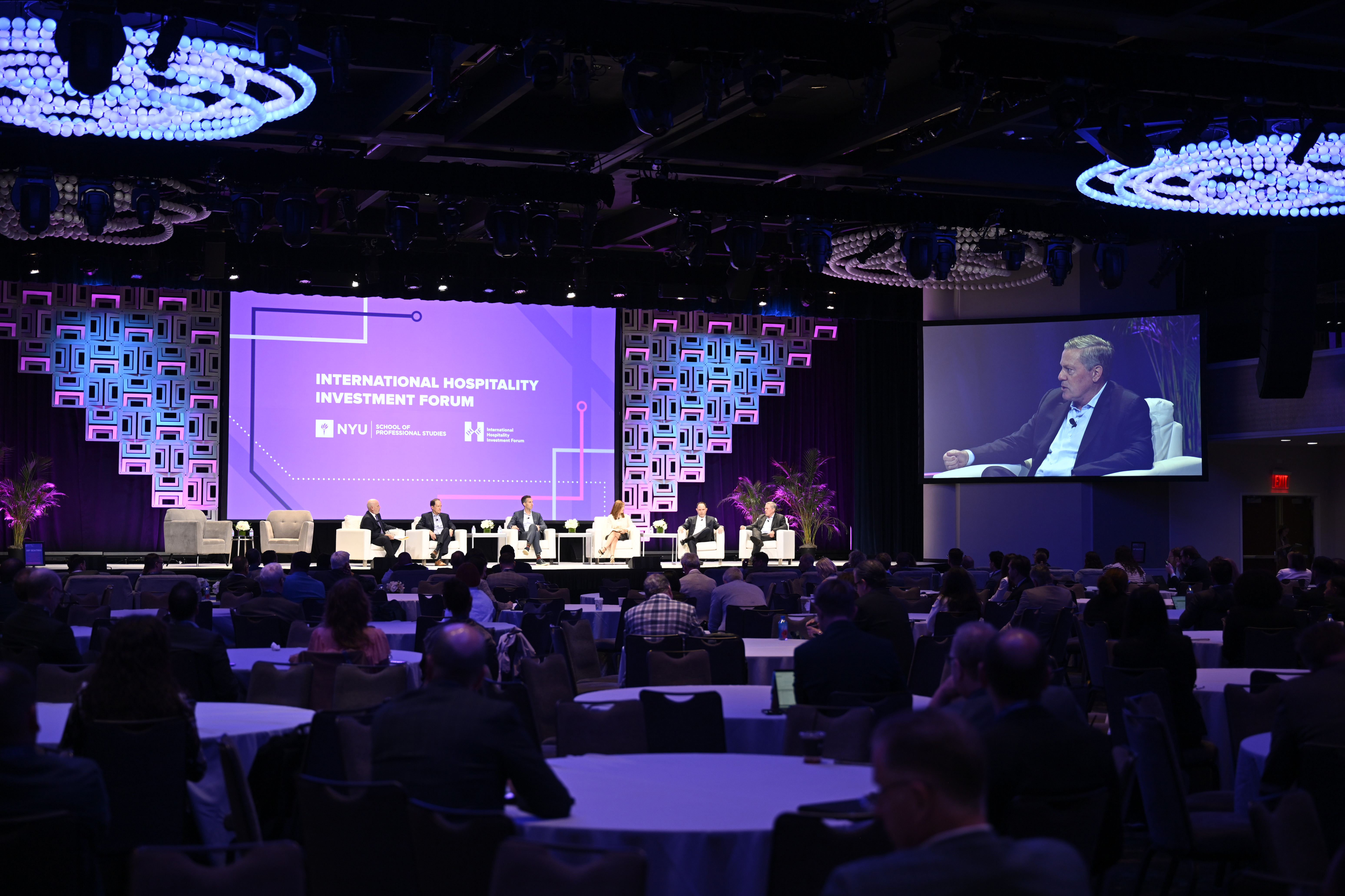 Hotel executives participate on a panel during the 2025 NYU International Hospitality Investment Forum. Aimbridge Hospitality CEO Craig Smith (highlighted on video) speaks during a session on controlling costs. (Matt Rickman, Questex)