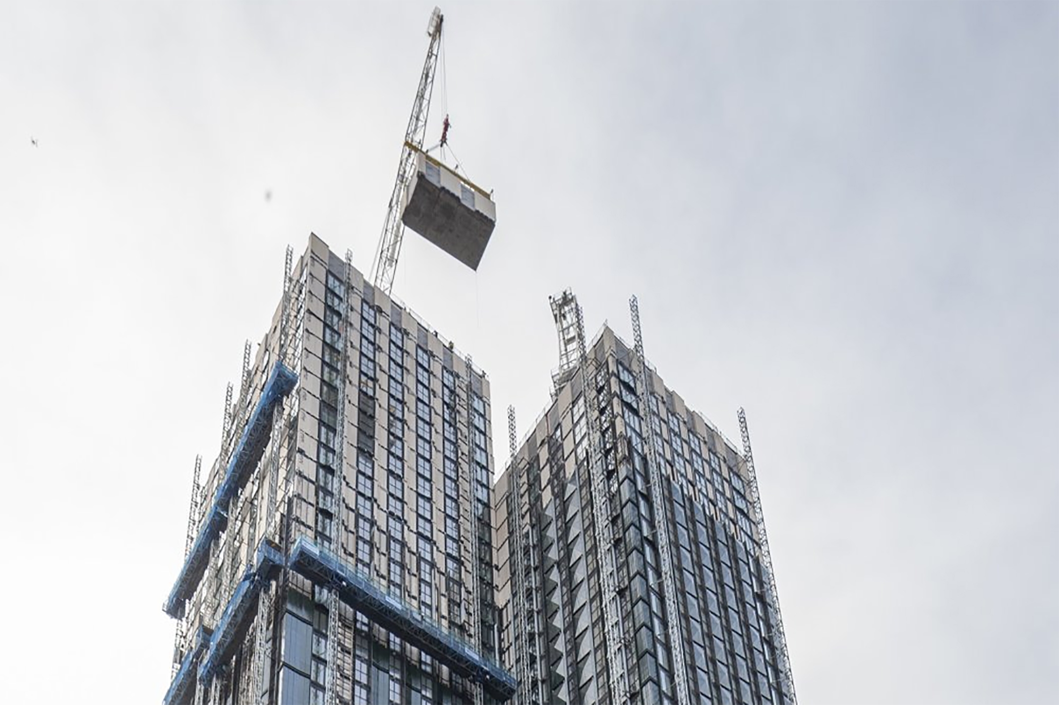 A crane lifts the final module on a London residential building that&#39;s expected to be the world&#39;s largest modular tower. (HTA Design)