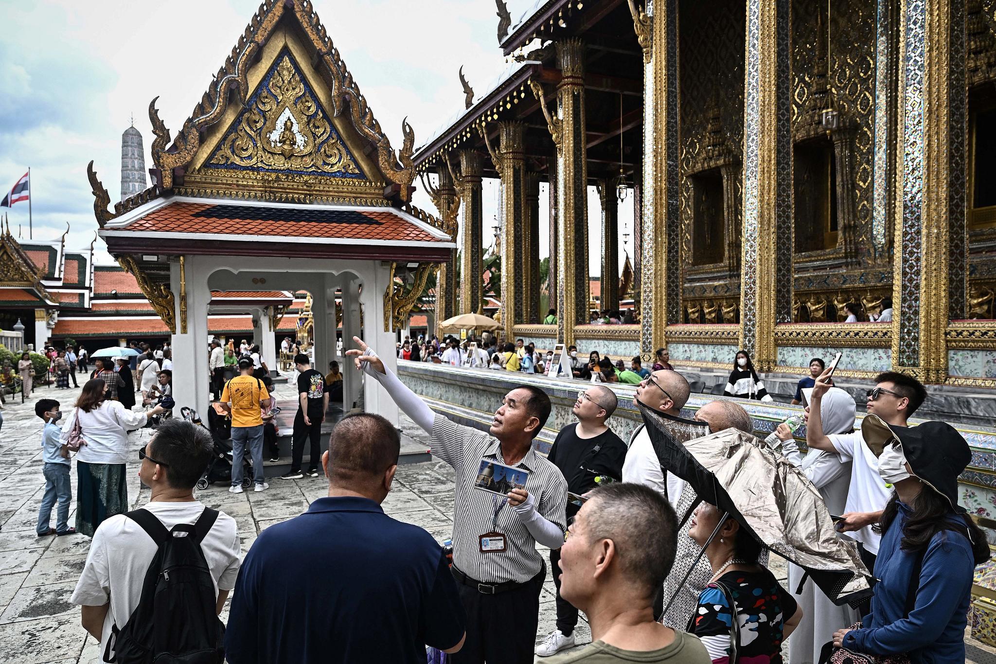 A Thai tour guide leads a group of Chinese tourists inside the Grand Palace in Bangkok. (Getty Images)