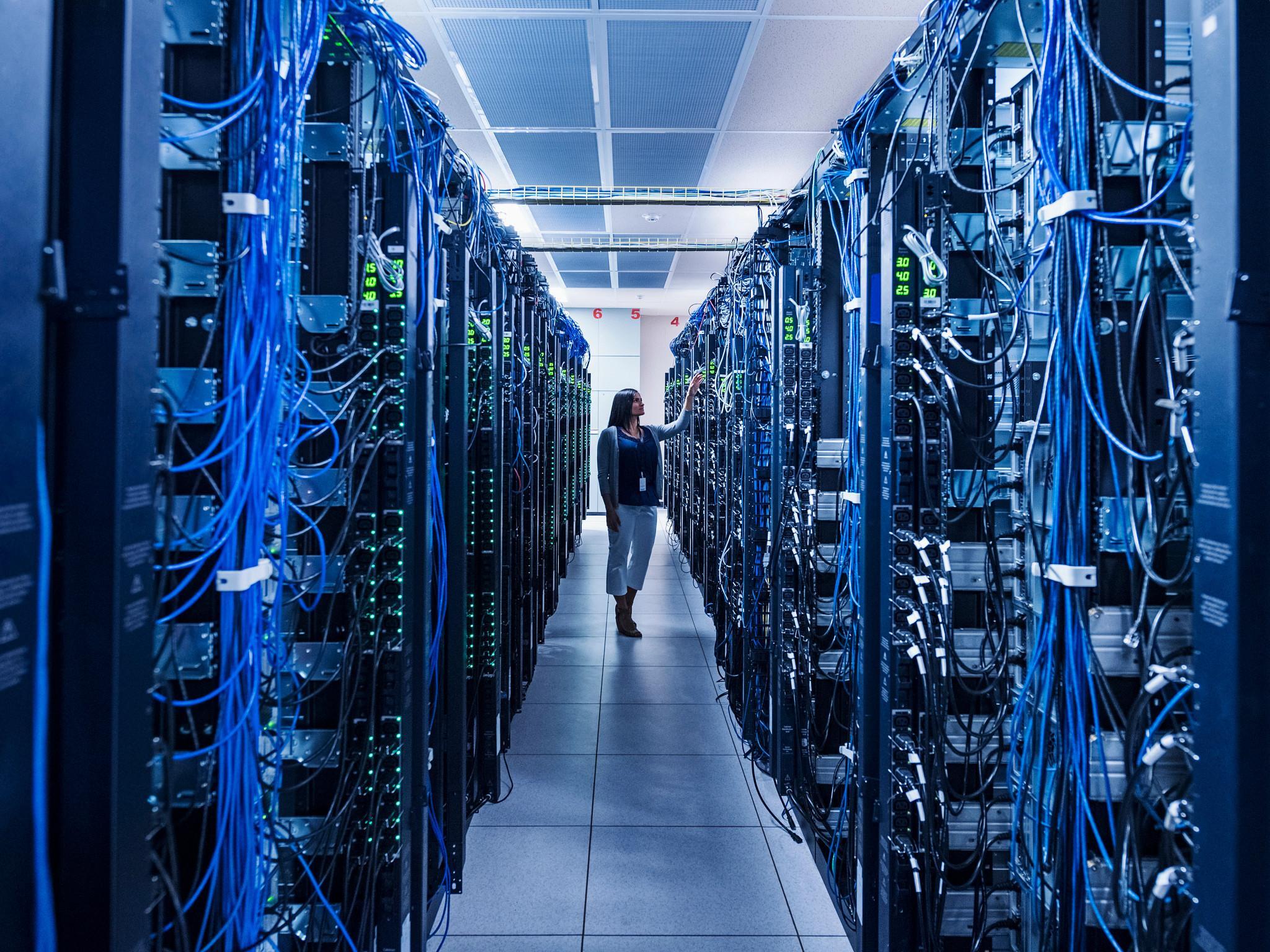 Woman standing in aisle of server room (Getty Images)