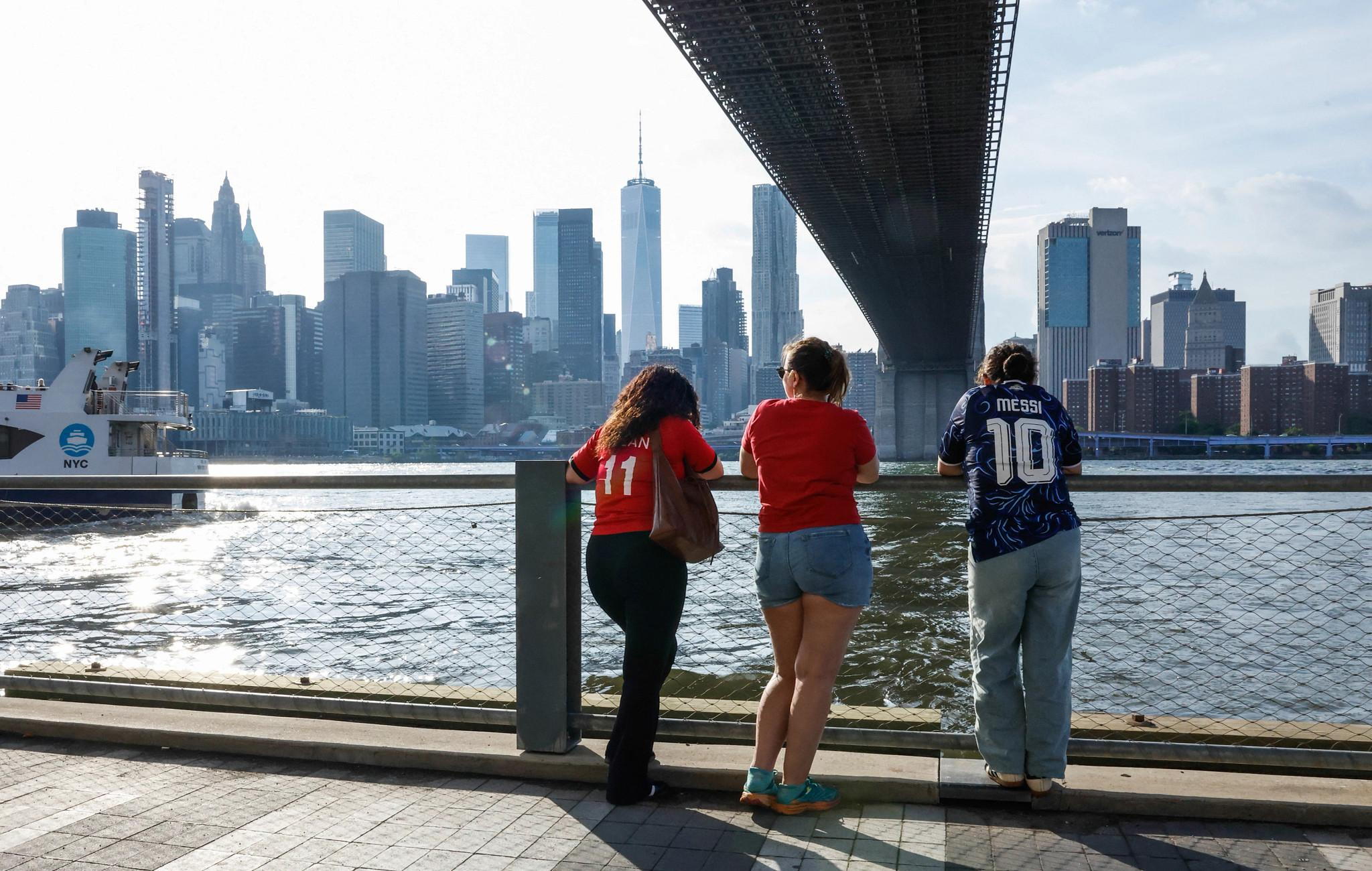 People wearing football jersey take a break from watching the World Cup quarterfinal football match between England and Norway at a fan zone in DUMBO (Down Under the Manhattan Bridge Overpass), a neighborhood in Brooklyn, New York, on July 11, 2026. (Photo by kena betancur / AFP via Getty Images) (AFP via Getty Images)